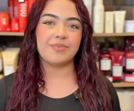 Estilista del salón frente a la estantería de productos profesionales